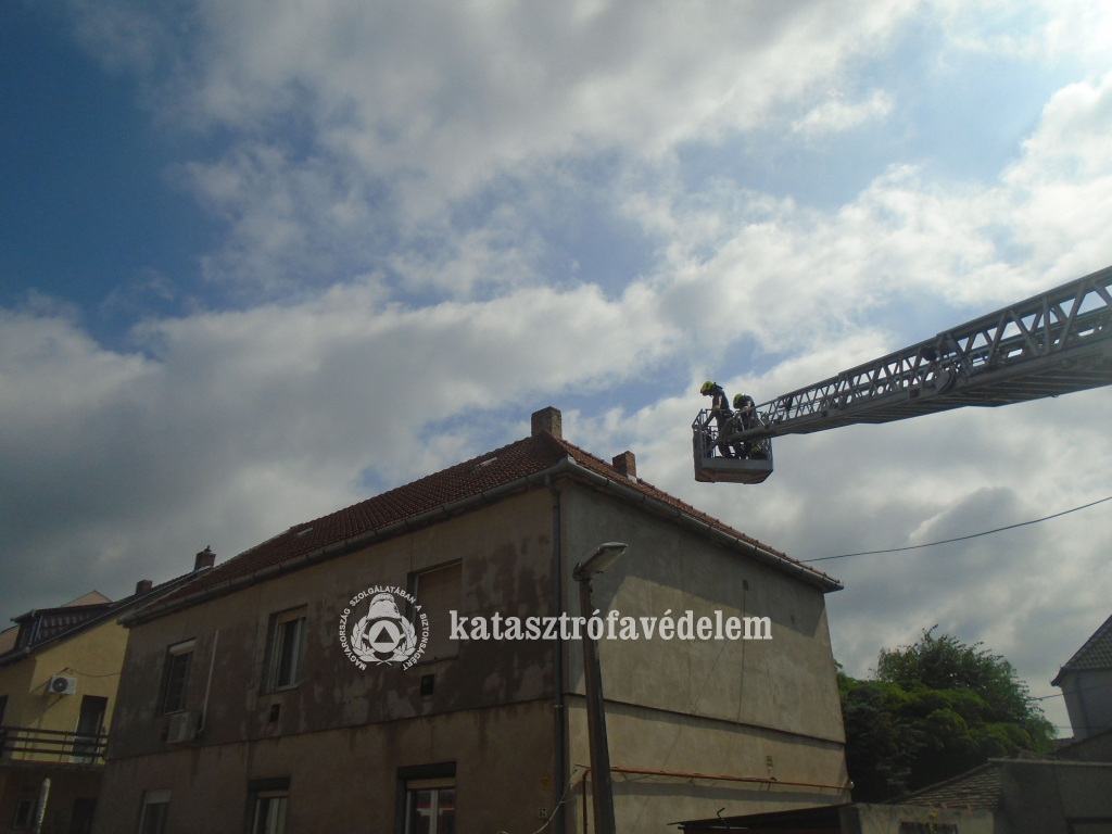 tűzoltók a magasból mentő kosárban, a háztetőnél