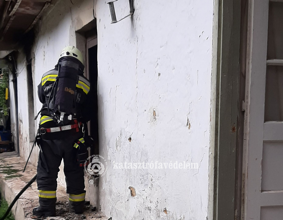 tűzoltó áll a ház ablakánál