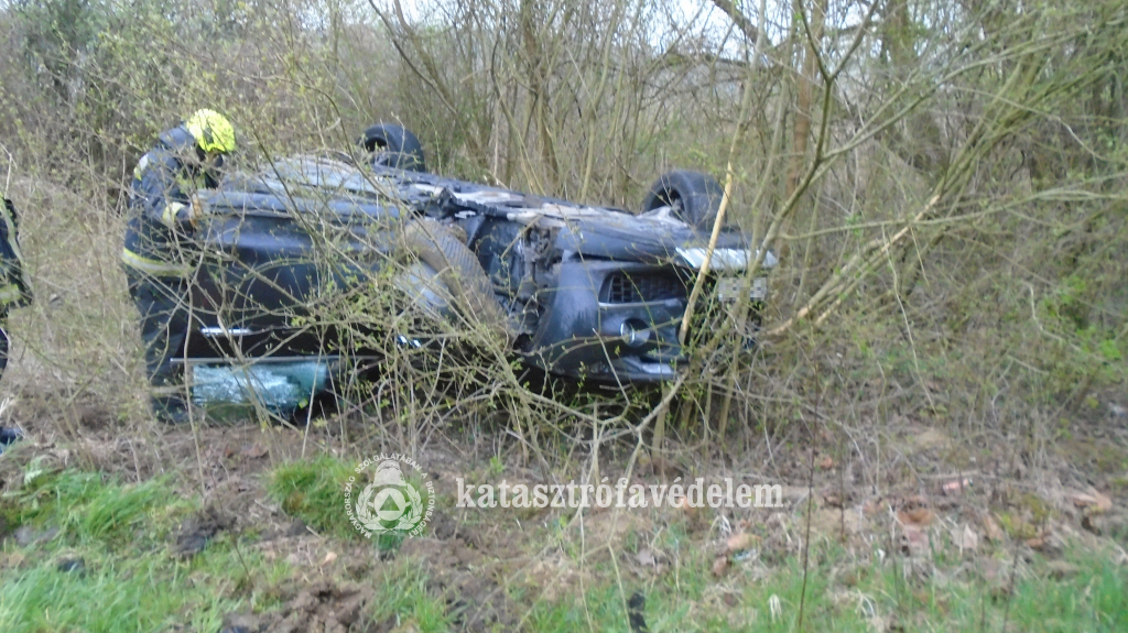 tetejére borult autó a bokorban, tűzoltó