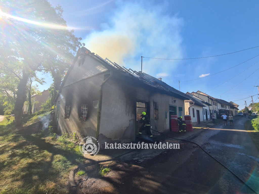 a még füstölő épületet a bejáratnál oltja egy tűzoltó