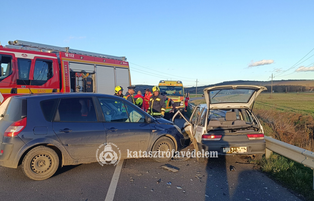 összeütközött személyautók, mögöttük tűzoltók, mentősök, tűzoltó- és mentőautó