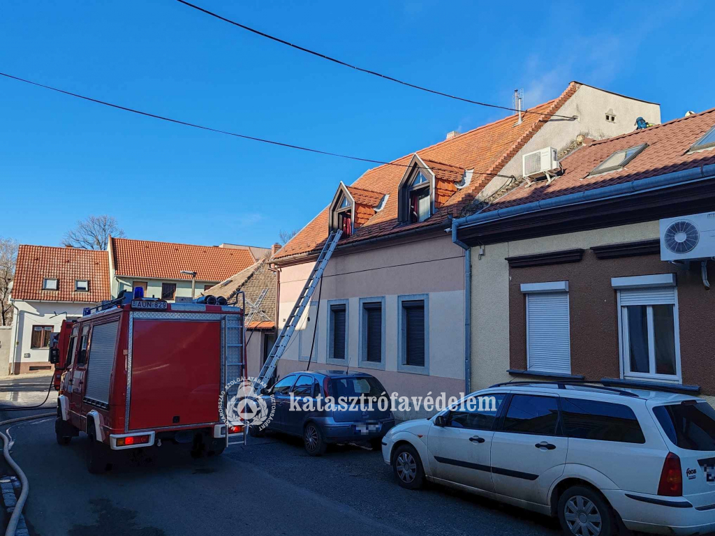 utcakép tűzoltóautóval, füstölő háztetővel