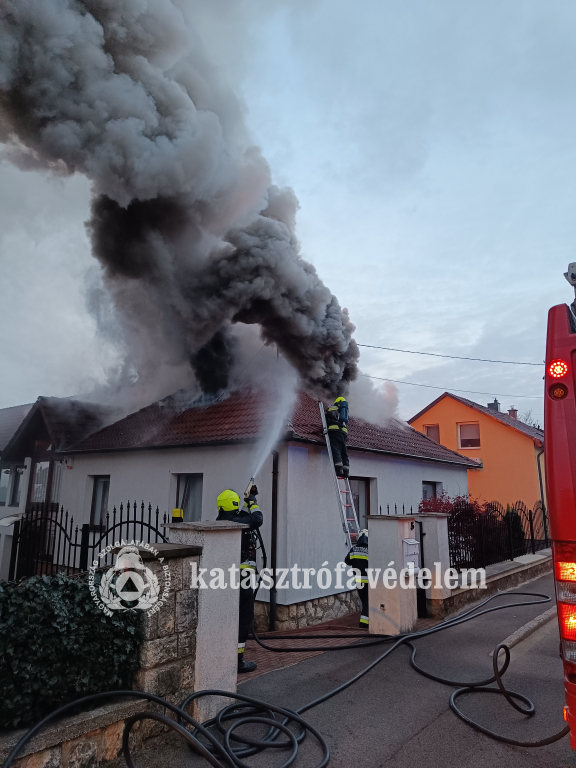 tűzoltók oltják a füstölő háztetőt