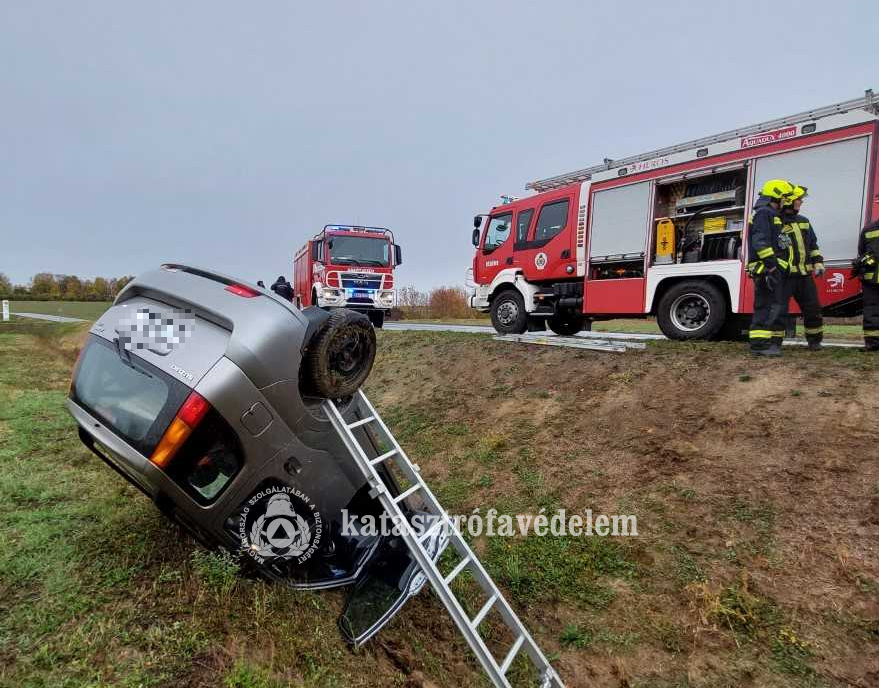 felborult autó az árokban, az úton tűzoltók, tűzoltóautók