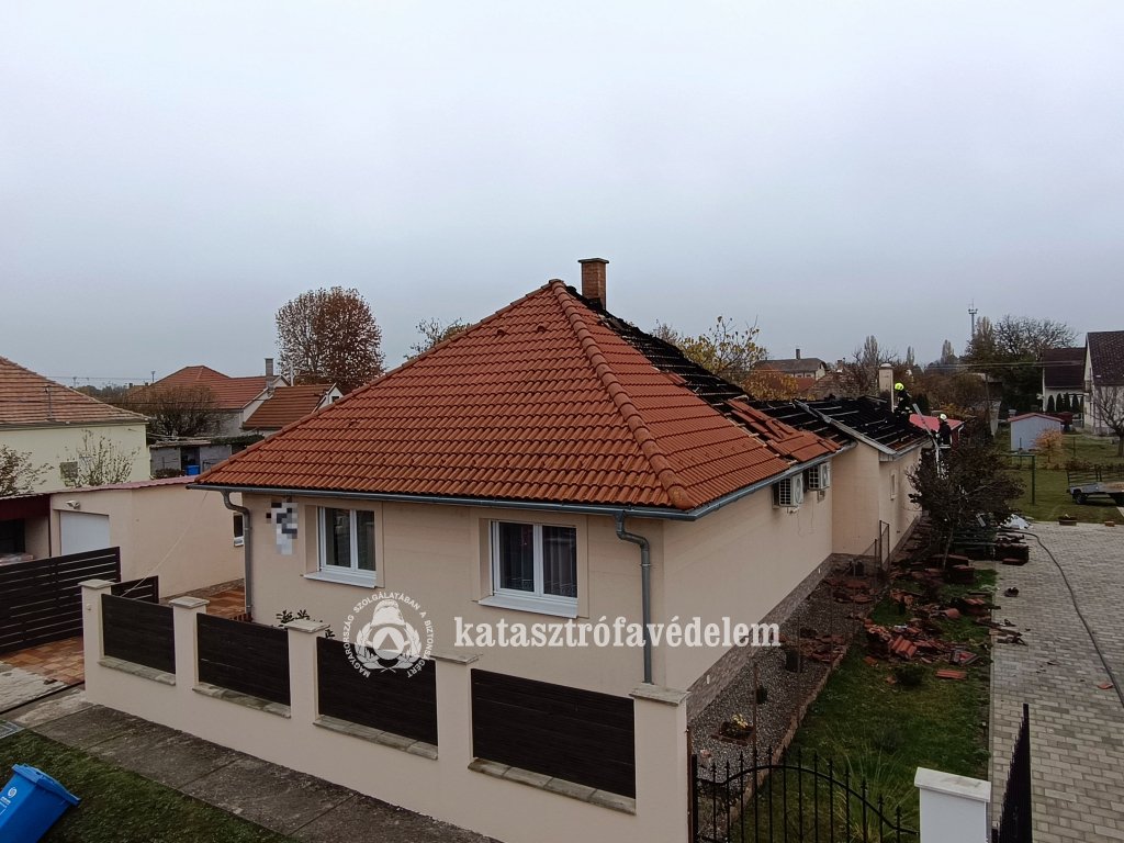 a tűzzel érintett családi ház, a tetőn tűzoltók