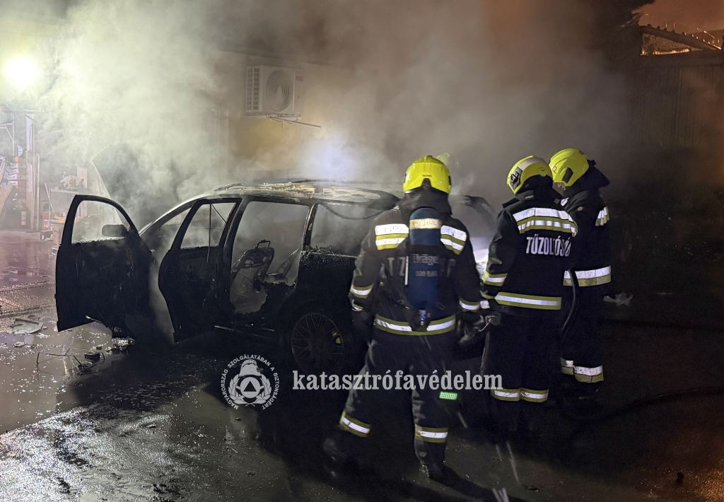tűzoltók a kiégett autó mellett
