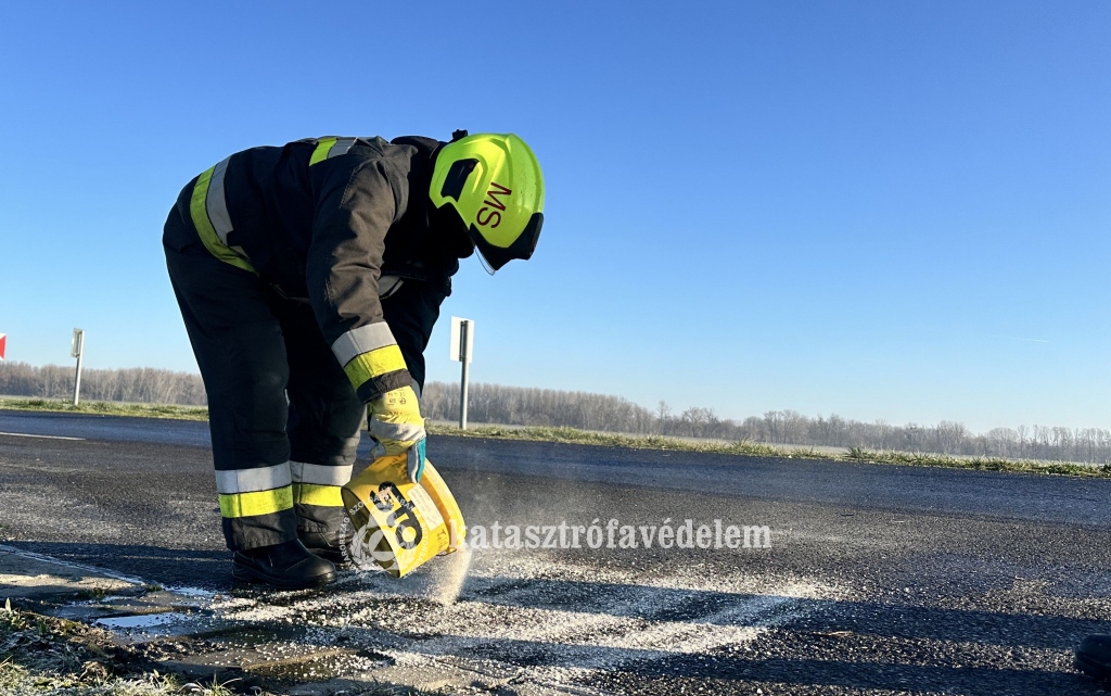 tűzoltó szórja az úttestet