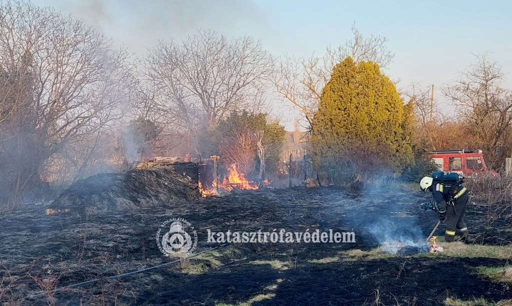 tűzoltó kézi szerszámmal oltja a szabadtéri tüzet