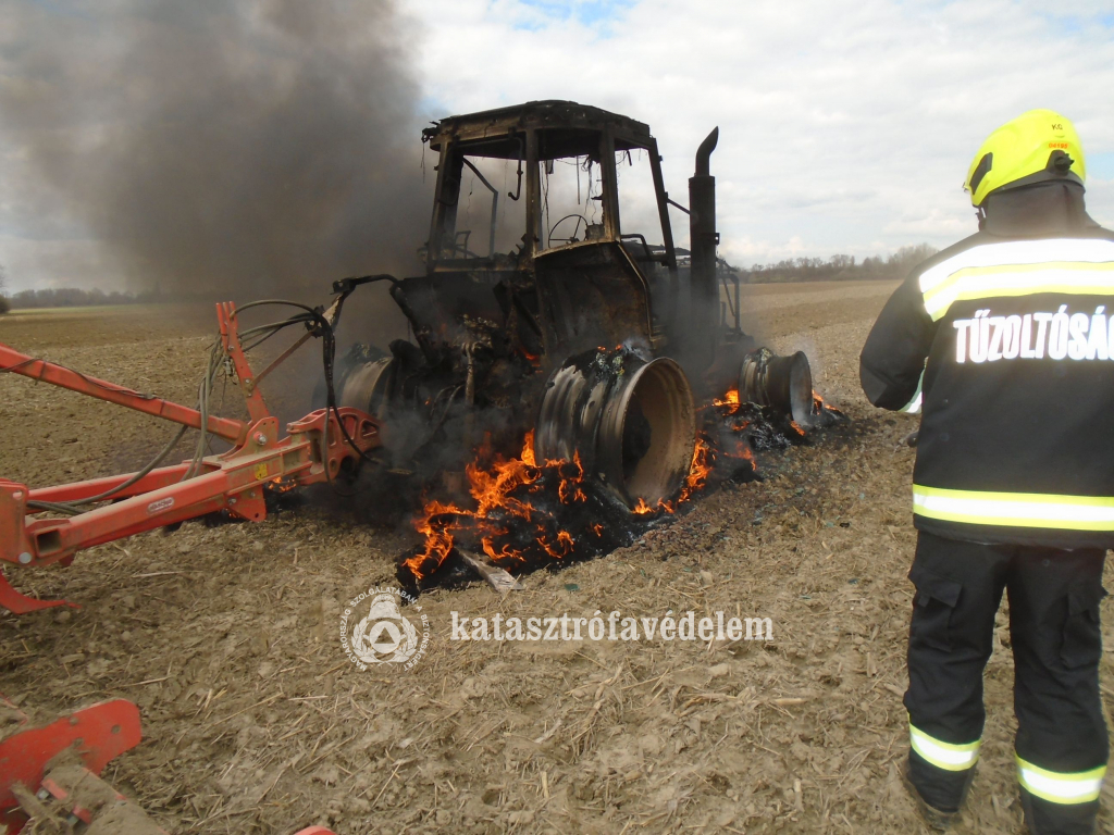 tűzoltó az égő traktor mellett